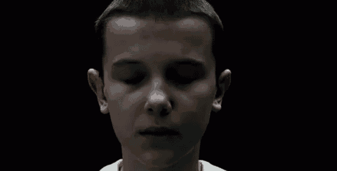 a close up of a young boy with his eyes closed in a dark room .