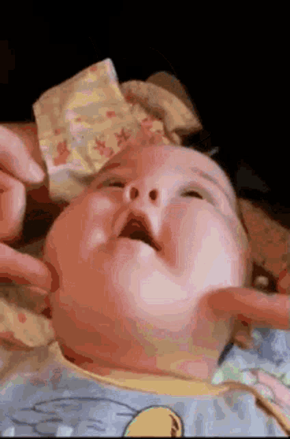 a close up of a baby 's face with a person holding it 's chin .