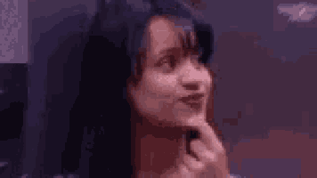 a woman is holding her hand to her chin and making a funny face .