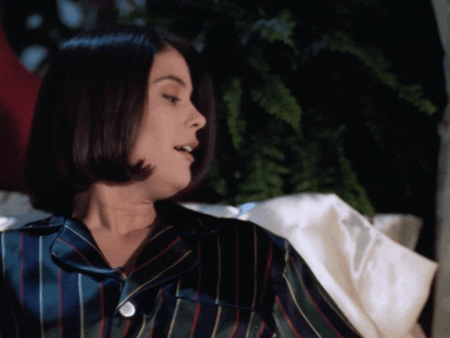 a woman wearing a striped pajama top is sitting on a couch