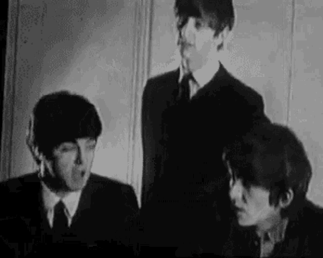 a black and white photo of the beatles in suits and ties .