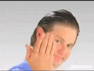 a man in a blue shirt is holding his hand to his face and smiling .