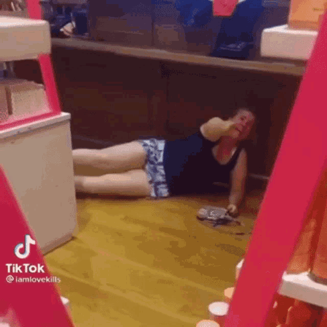 a woman is laying on the floor in a store and making a funny face .
