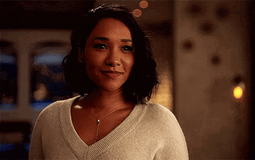 a close up of a woman wearing a sweater and necklace smiling .