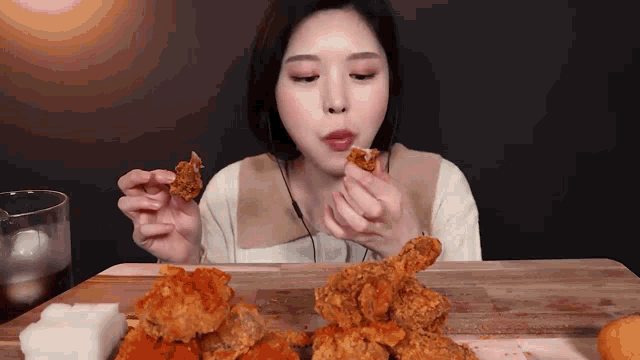 a woman is eating fried chicken on a table