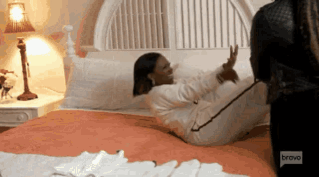 a woman is laying on a bed with bravo written on the bottom right