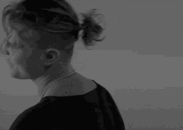 a black and white photo of a man with a ponytail and a chain around his neck
