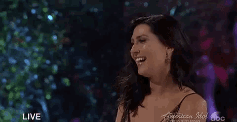 a woman is applauding in front of a live audience on american idol