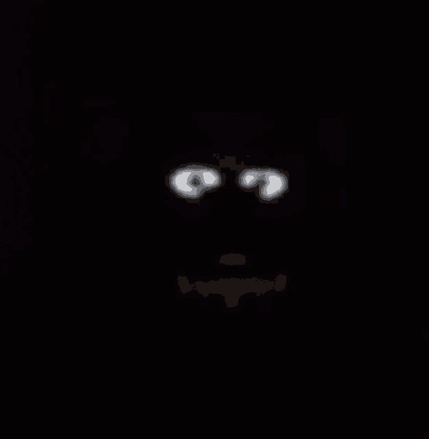 a close up of a cartoon character 's face in the dark with glowing eyes .