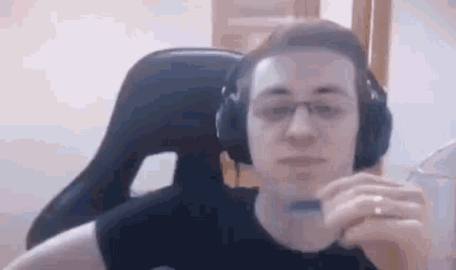 a man wearing headphones and glasses is sitting in a gaming chair .