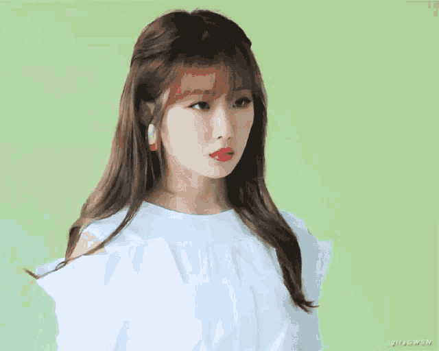 a woman wearing a white shirt with ruffles on the sleeves is looking at the camera