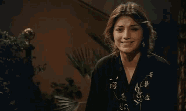 a woman wearing a black shirt with flowers on it smiles