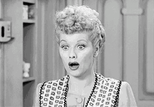 a black and white photo of a woman with her mouth open and a surprised look on her face .