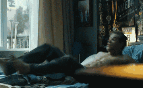 a shirtless man laying on a bed with a boom sign on the wall behind him