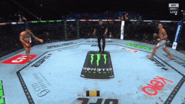 two men are fighting in a boxing ring with a monster energy can in the center