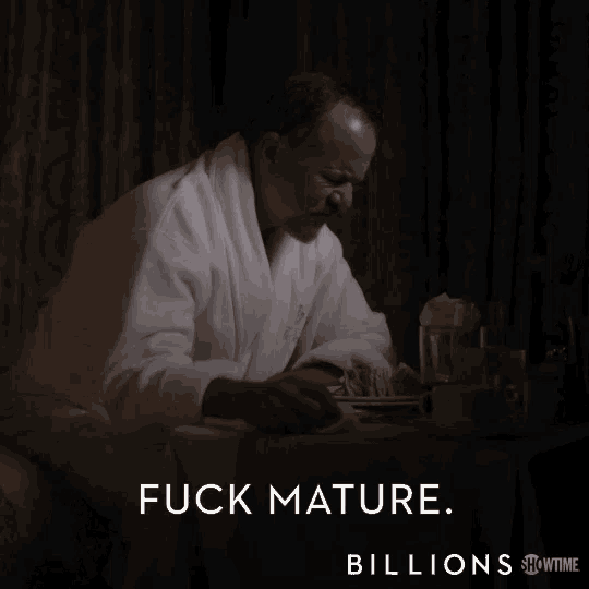 a man in a bathrobe sits at a table with the words " fuck mature billions " above him