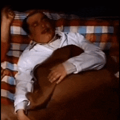 a man in a white shirt and tie is sleeping in a bed
