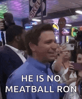 a man in a blue shirt is standing in front of a crowd .