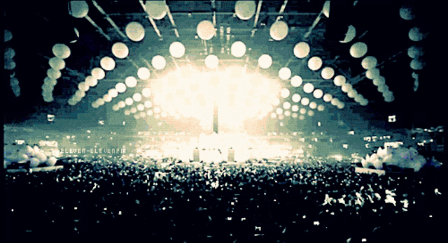 a crowd of people are gathered in a dark room with a large light shining on them