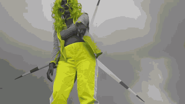 a woman with green hair and yellow pants holds a spear