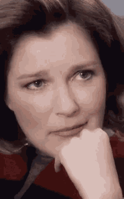 a close up of a woman 's face with her hand under her chin .