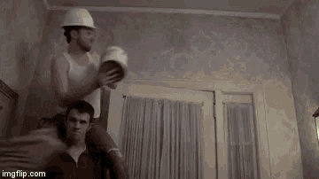 a man in a hard hat is carrying another man on his shoulders .