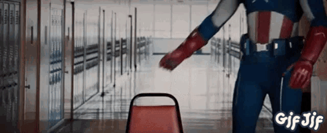 a man in a superhero costume is standing in a hallway next to a chair .