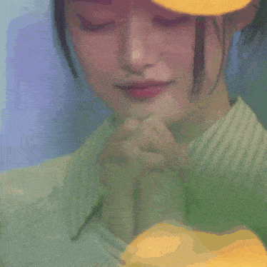 a close up of a woman with her eyes closed and her hands folded in prayer .