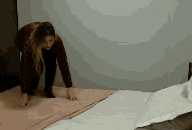 a woman laying on a bed with a pink blanket on it