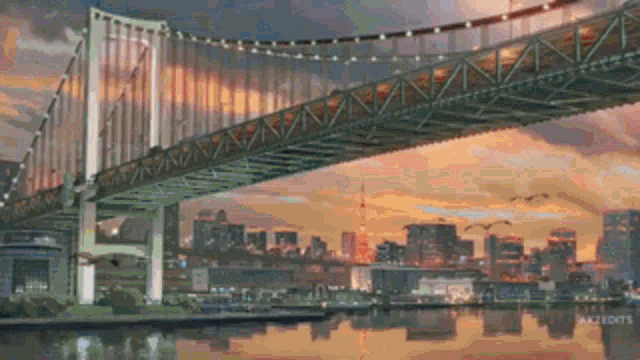 a bridge over a body of water with a city in the background at sunset