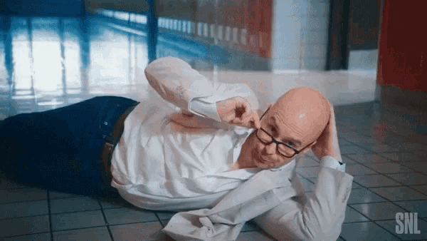 a bald man with glasses is laying on the floor