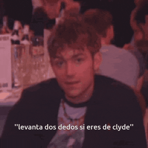 a man sitting at a table with the words levanta dos dedos si eres de clyde on the bottom