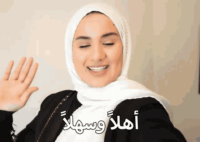 a woman wearing a white hijab and a black jacket is smiling
