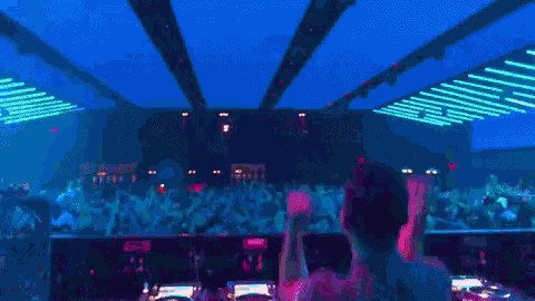 a dj stands in front of a crowd of people at a club