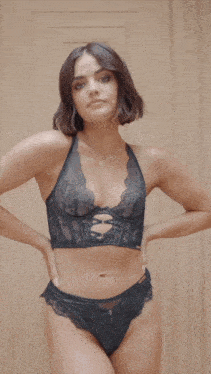 a woman in black lingerie is standing in front of a wooden wall