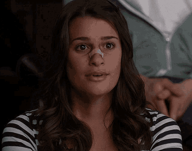 a woman with a bandage on her nose and a striped shirt
