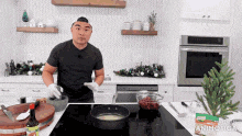 a man in a black shirt is cooking on a stove in a kitchen .