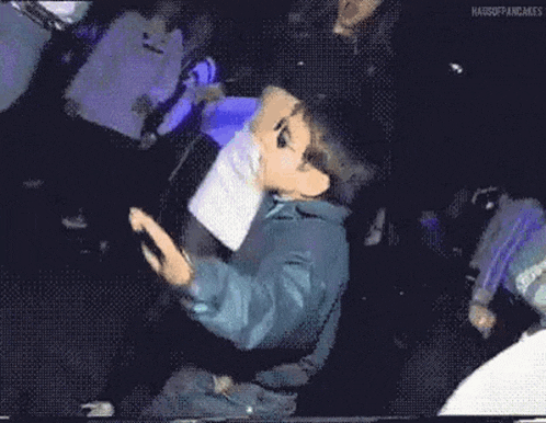 a young boy wearing sunglasses is dancing in a crowd of people .