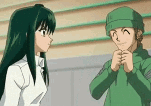 a man and a woman are standing next to each other in a room . the man is wearing a green hat .