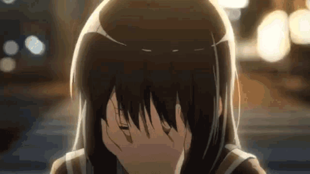 a girl is covering her face with her hands while standing on a sidewalk .