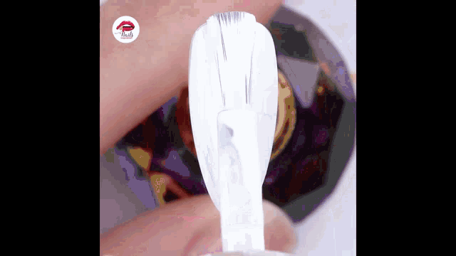 a bottle of white nail polish is being applied to a finger