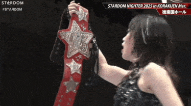 a female wrestler is holding a red belt with stars on it