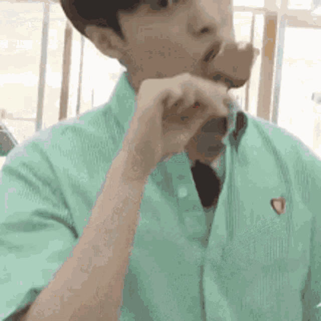 a man in a green shirt is eating a hamburger .