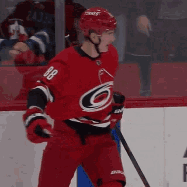 a hockey player wearing a red jersey with the number 88 on it is standing on the ice .