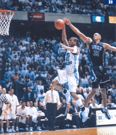 a duke basketball player is jumping in the air while another player tries to stop him