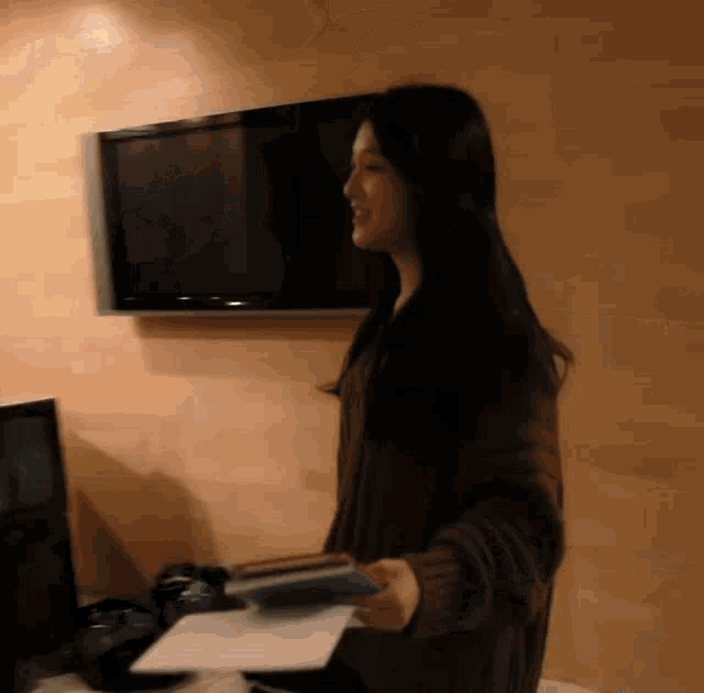 a woman is standing in front of a television holding a piece of paper