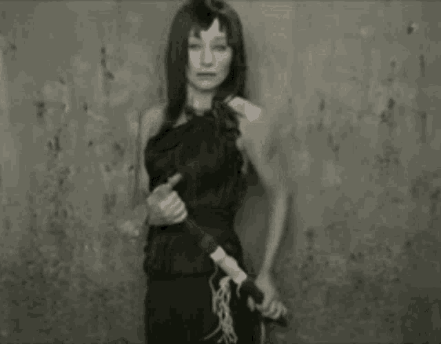 a woman is standing in front of a wall holding a sword .