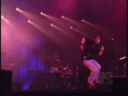 a man is singing into a microphone on a stage with purple lights behind him .