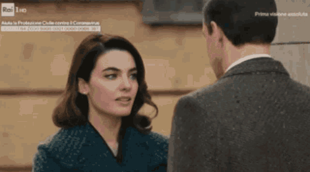 a man and a woman are looking at each other in a tv show