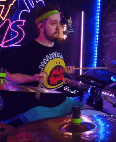 a man wearing an all that shirt playing drums